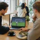 Två vuxna använder ett webbaserat fotbollsspel på ett kafé