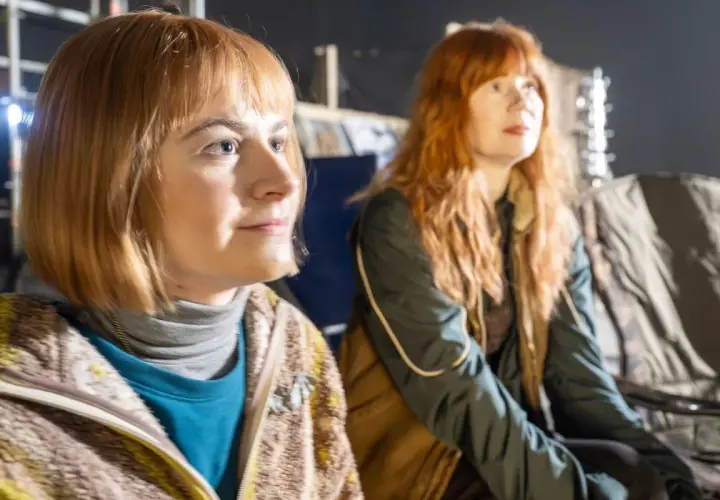 Matilda Gross med rött hår och en annan kvinna sitter i en studio.