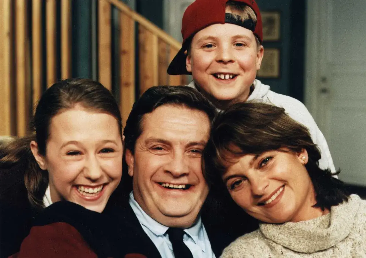 Familjen Svensson ler glatt mot kameran. Pappa, mamma, dotter och son, alla samlade för ett klassiskt familjeporträtt.